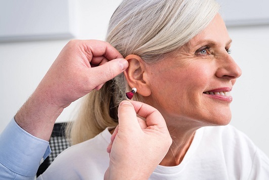 Ältere Frau erhält ein modernes Hörgerät zur Verbesserung ihres Hörvermögens eingesetzt.